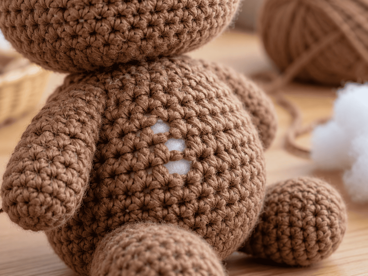 Close-up of a brown amigurumi toy with visible holes and white stuffing showing through.